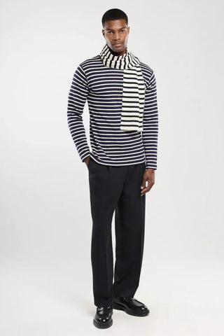 Man wearing navy and white striped long-sleeve shirt, matching striped scarf, black trousers and shoes