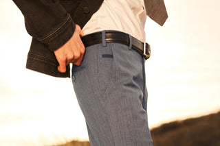 Close-up of man wearing blue dress pants with black leather belt and casual jacket outdoors