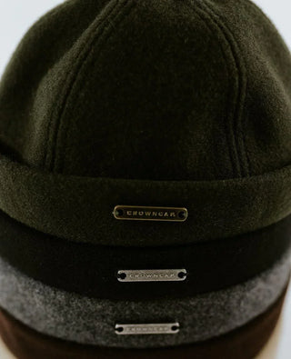 Stack of wool beanies in green, black, and gray with Crowncap metal labels