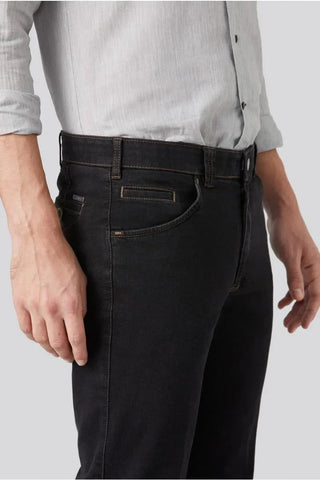 Man wearing dark slim-fit jeans and a light gray button-up shirt, close-up view