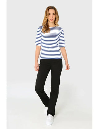 Woman wearing a blue and white striped Breton shirt with black pants and white sneakers