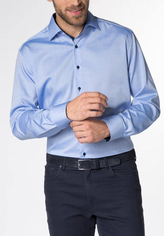Man wearing a light blue long sleeve modern fit dress shirt and dark trousers