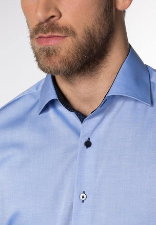 Close-up of man wearing light blue modern fit long sleeve dress shirt with contrasting buttons