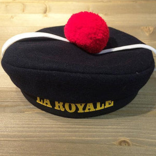 Navy blue French sailor beret with red pompom and LA ROYALE text on wooden surface