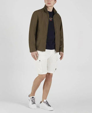 Man wearing olive nylon jacket, navy shirt, white cargo shorts, and white sneakers