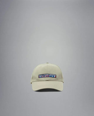 Beige nylon yachting cap with embroidered flags and logo patch on front, isolated on grey.