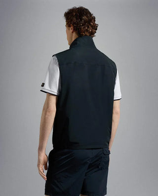 Man wearing navy nylon sleeveless vest and black shorts, back view, neutral background