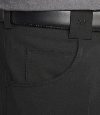 Close-up of black pants front pocket with black leather belt and embroidered M logo on belt loop